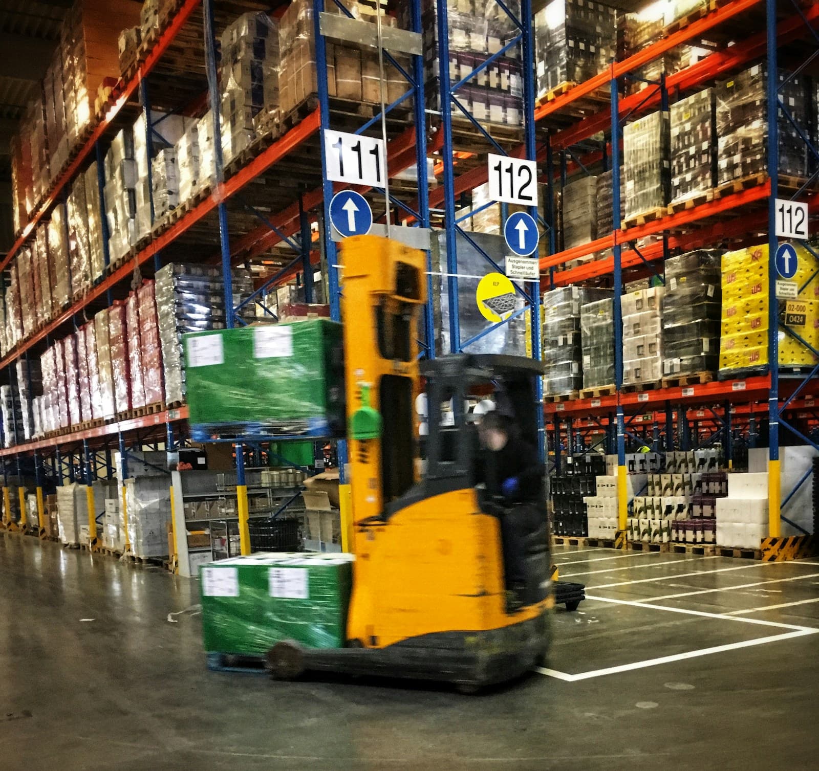 Modern logistics warehouse with racked pallets and forklift operations